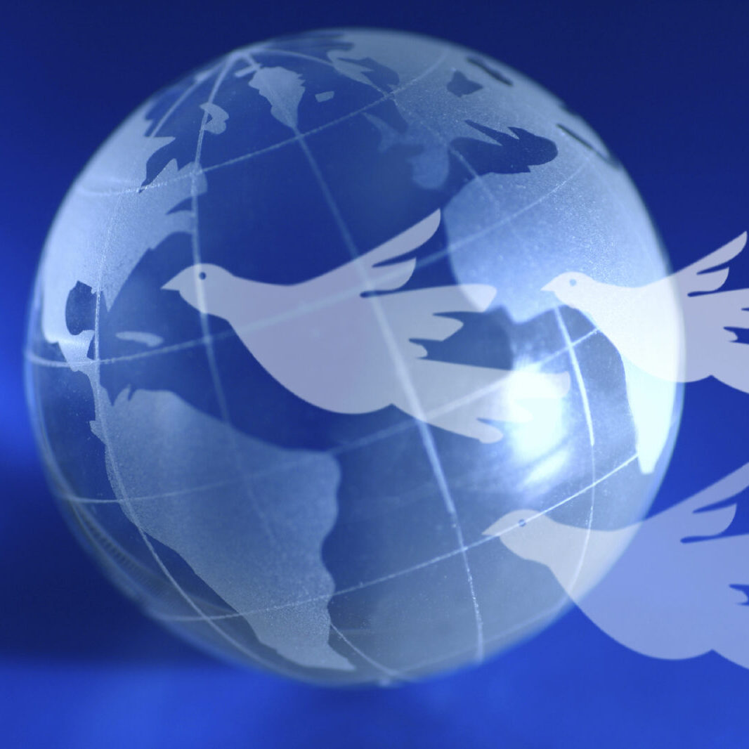 A blue globe with doves flying ahead. A global peace idea.